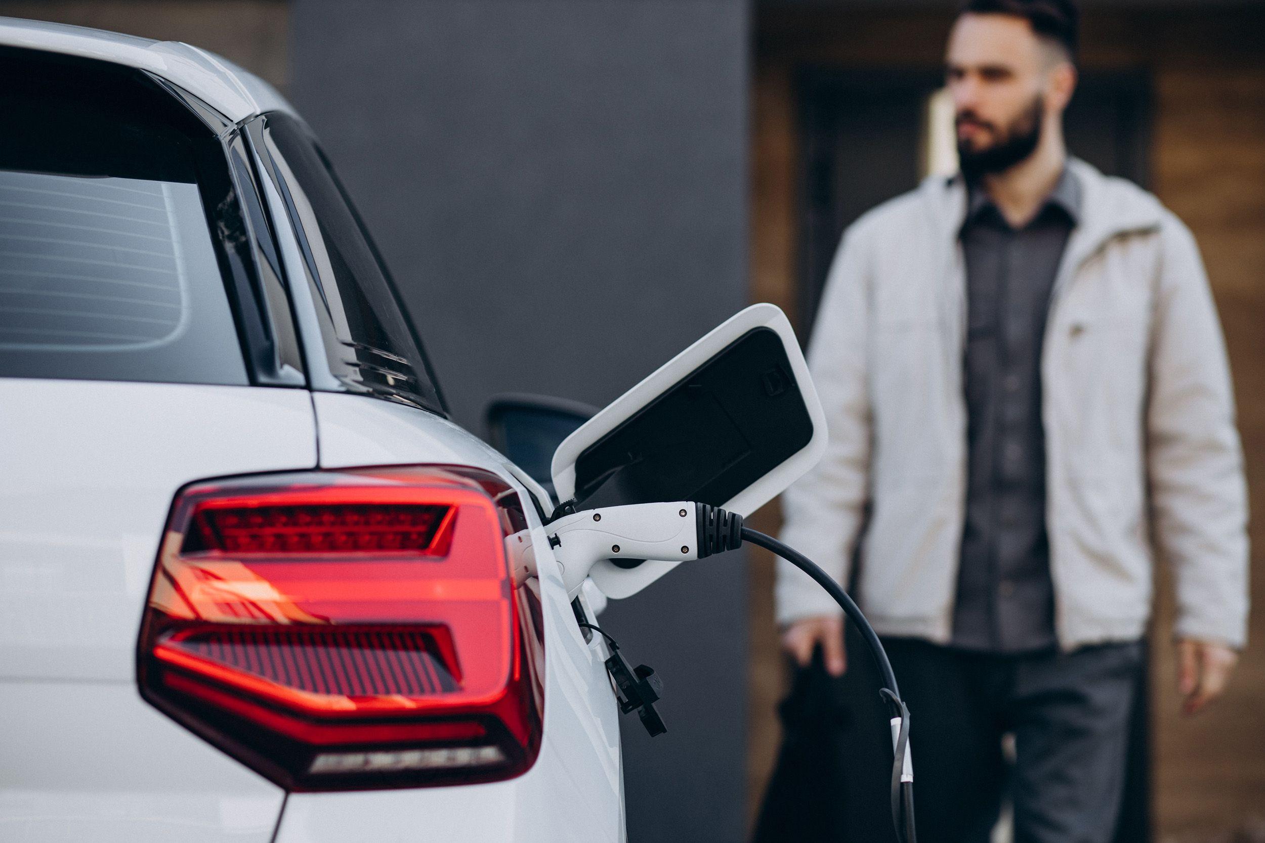 Mann vor E-Auto zuhause