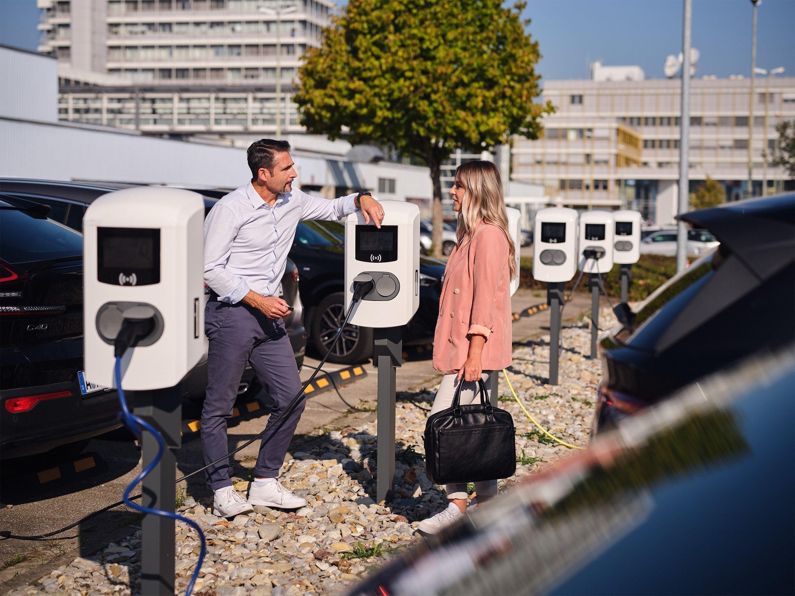 Kollegen unterhalten sich an Ladestation auf Firmenparkplatz