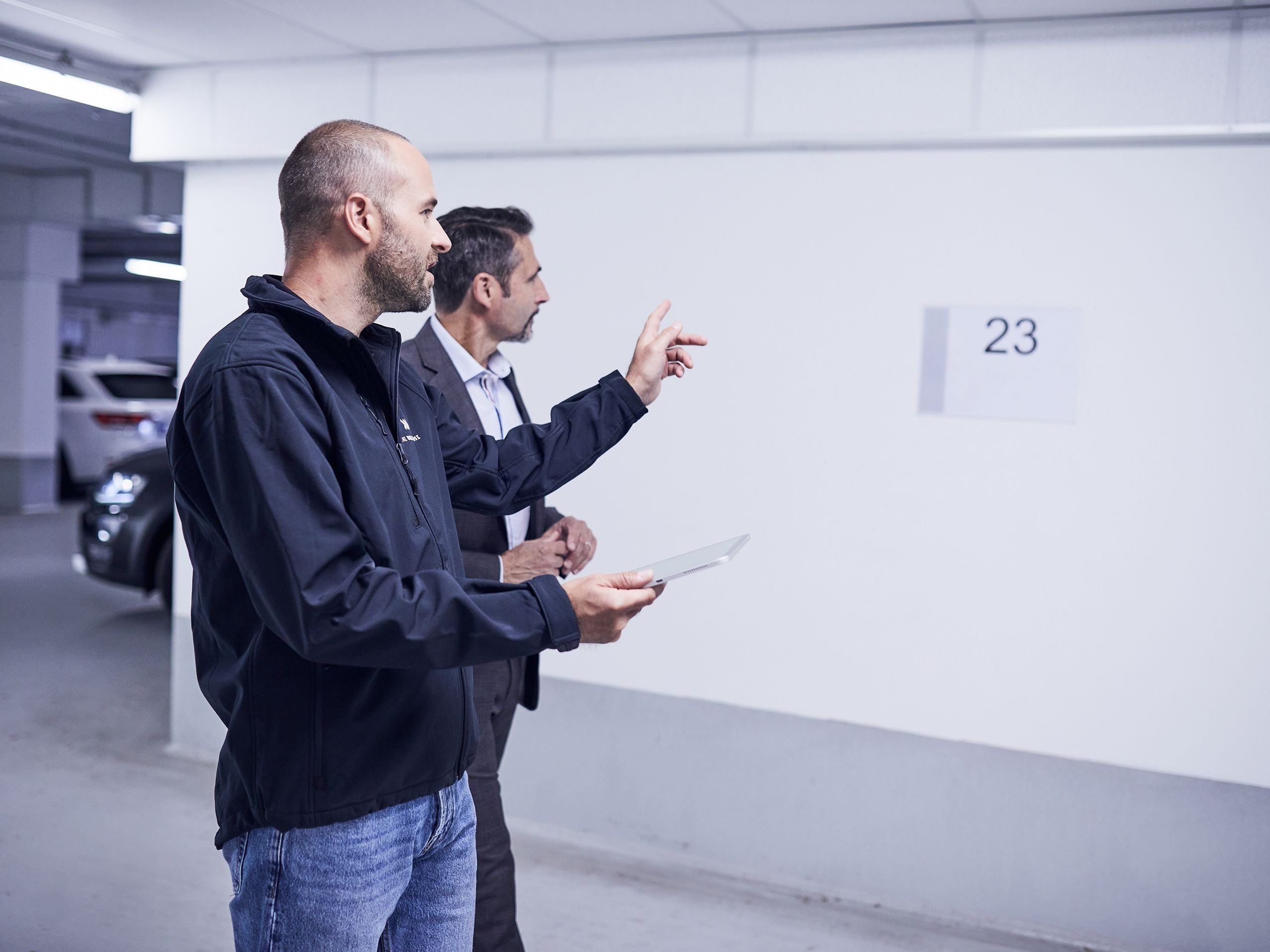 Elektriker und Kunde sprechen miteinander bei einer Begehung in der Tiefgarage