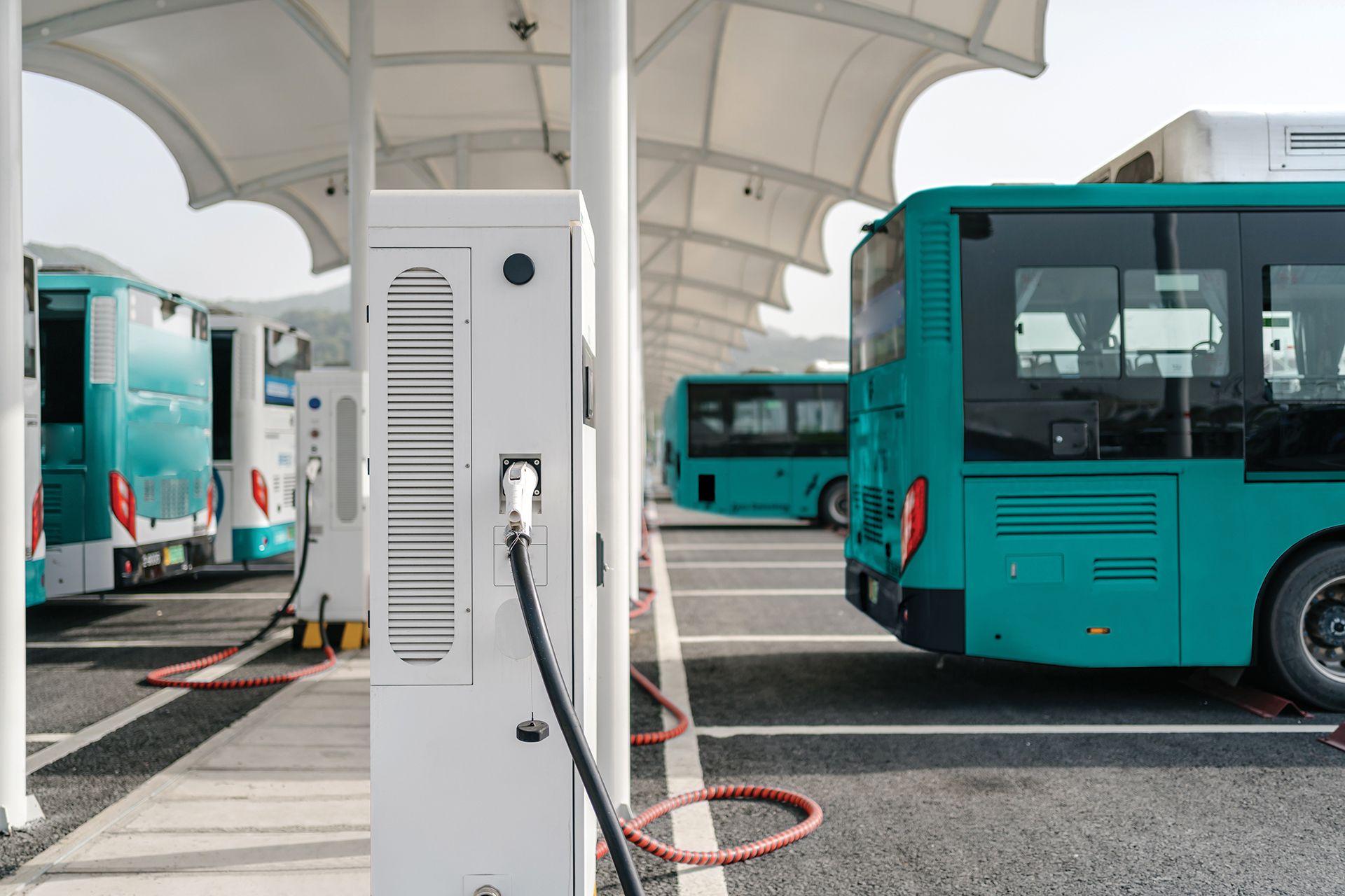 Electric buses charging at a bus depot under a canopy