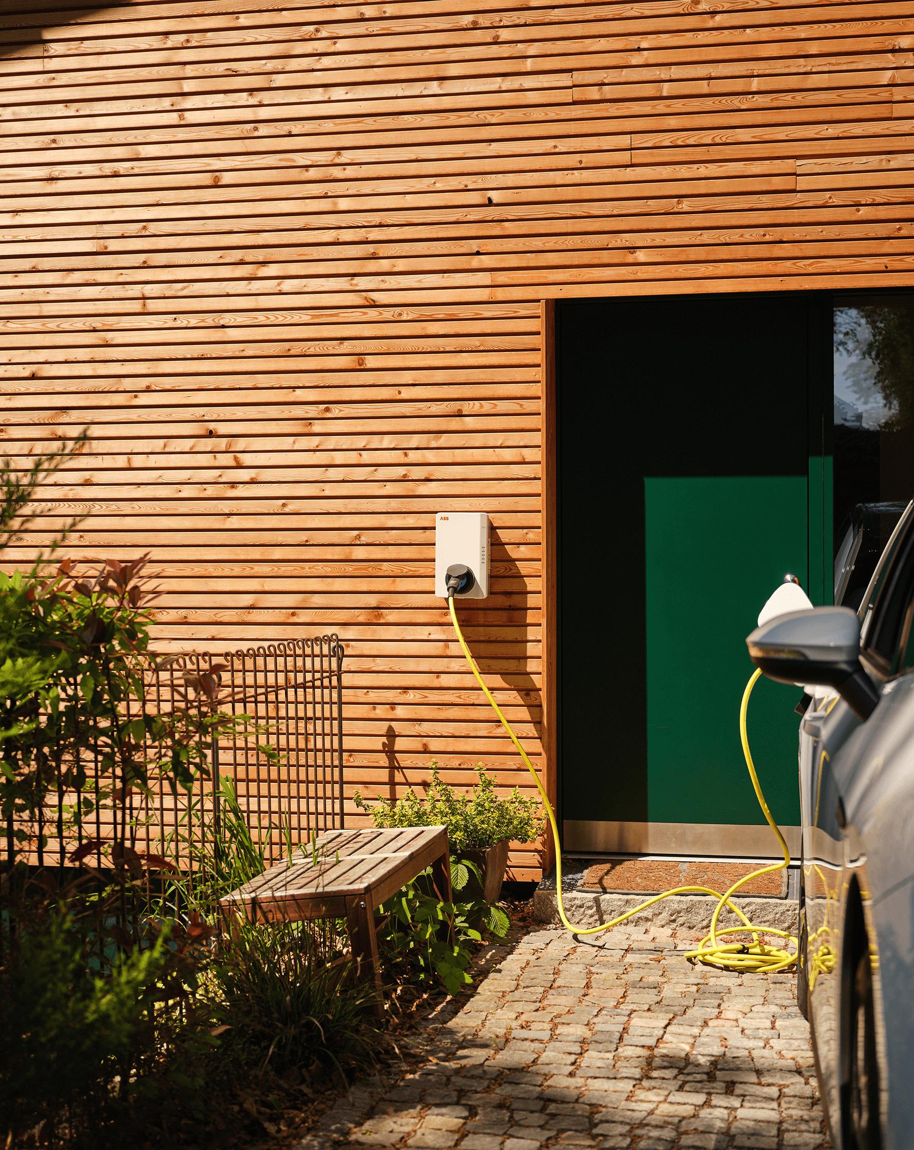 E-Auto lädt an Wallbox vor dem Haus