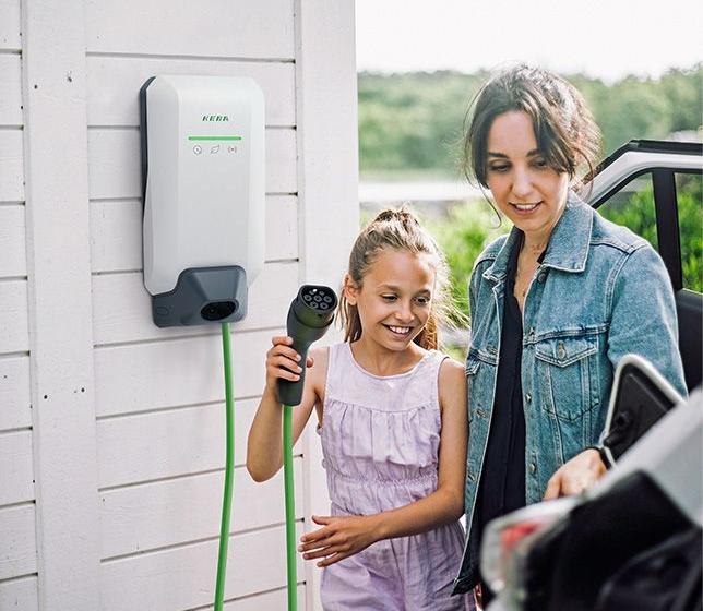 Frau und Kind steckt E-Auto an die Wallbox